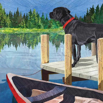 Black labrador dog on wooden dock with canoe looking over lake at trees in distance
