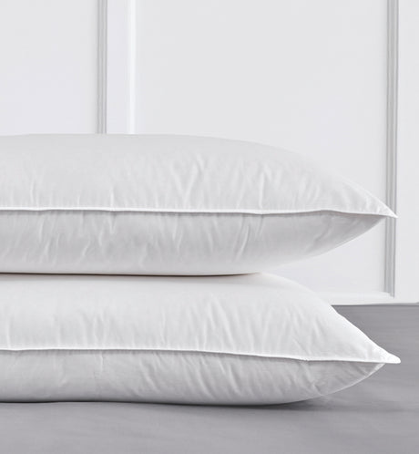 Two white pillows stacked on a light gray surface with a white background