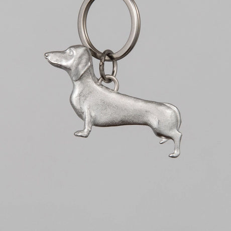 Silver dachshund-shaped keychain on a gray background
