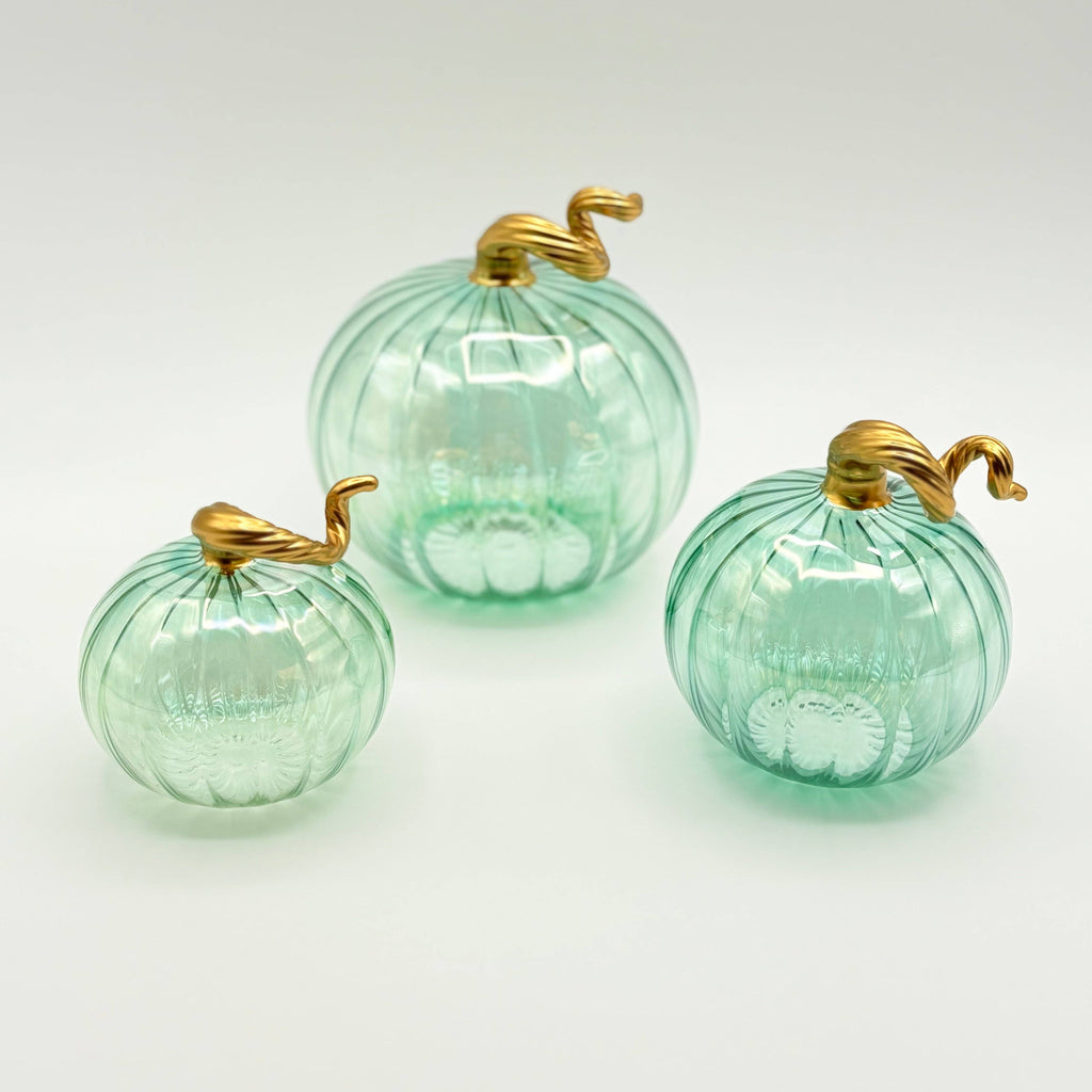 Three green glass pumpkins with gold stems on a white background