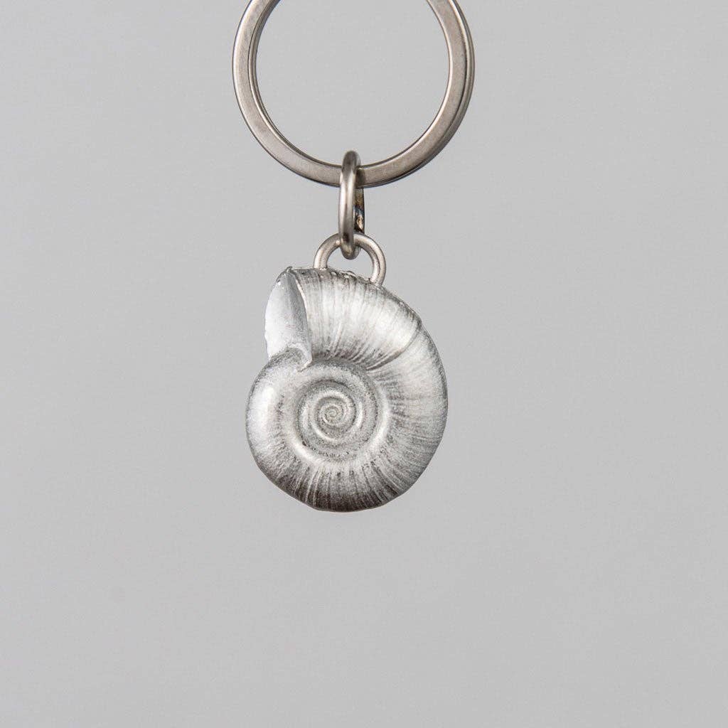 Keychain with a pewter spiral shell charm on a gray background