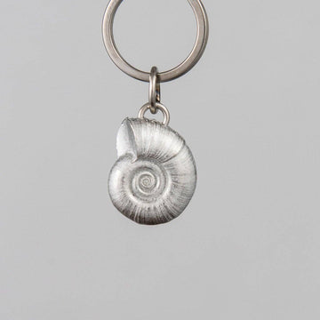 Keychain with a pewter spiral shell charm on a gray background