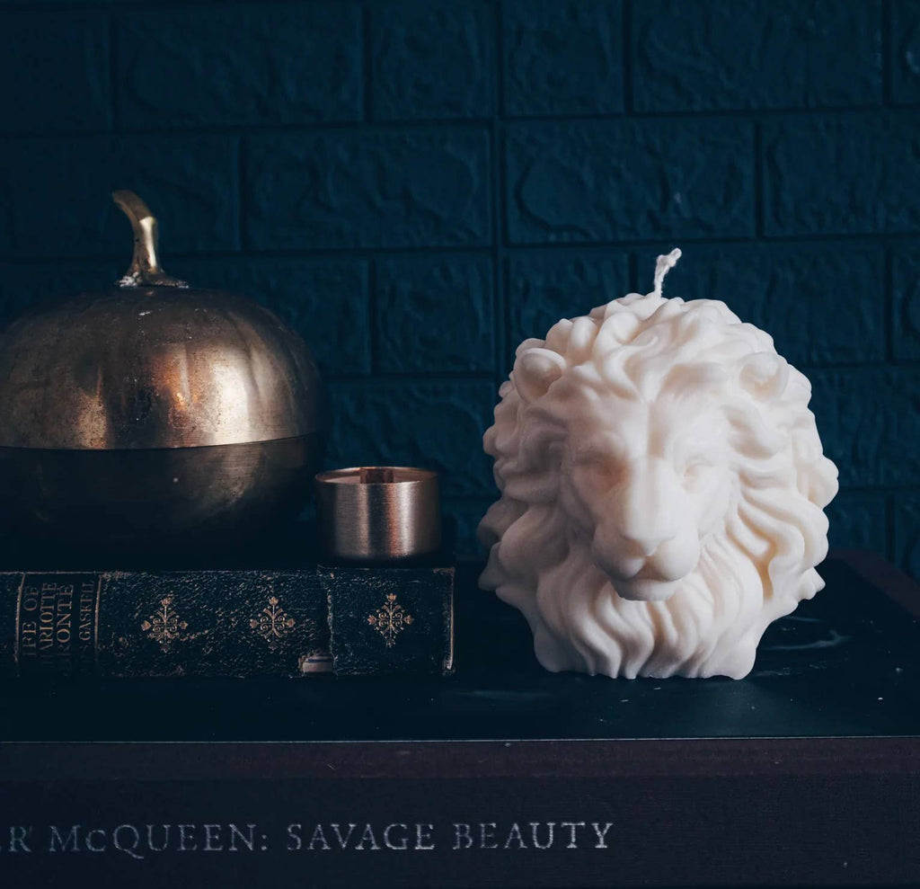 Candle shaped like a lion head on a dark surface with decorative elements.