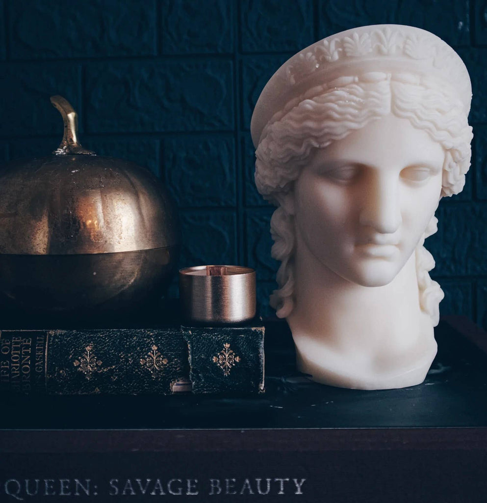 Bust of a classical figure with a pumpkin and candle on a dark textured background