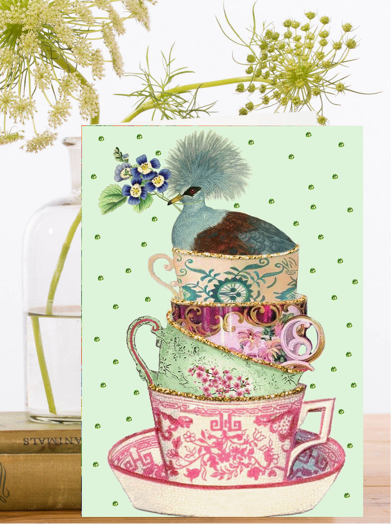 Decorative greeting card with stacked teacups and a bird on a light green background.