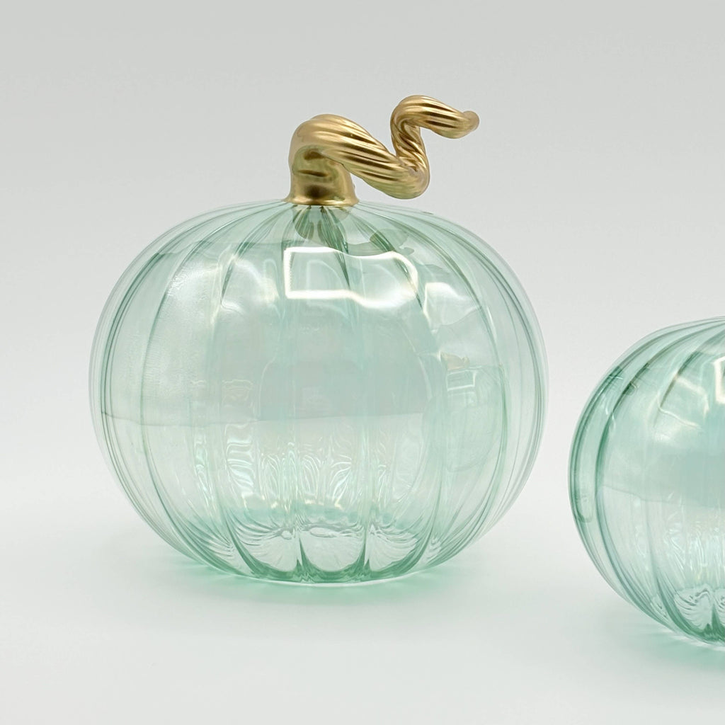 Green glass pumpkin with gold top on a white background