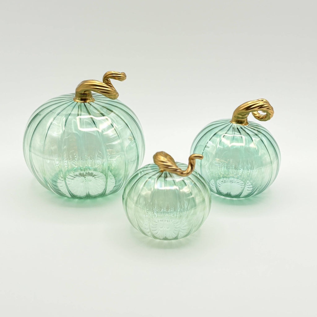 Three green glass pumpkins with gold stems on a white background