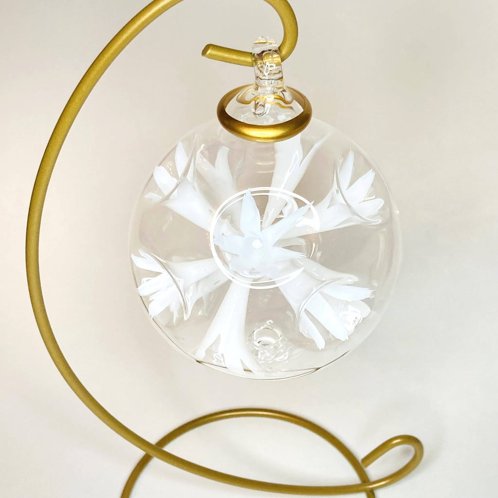 Decorative glass ball with floral design on a gold stand against a white background