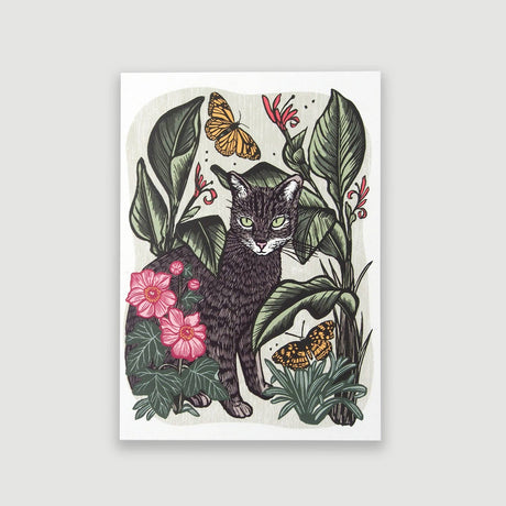 A vertical art print featuring an illustrated black cat surrounded by green tropical leaves, pink flowers, and two orange butterflies, shown against a light gray background.