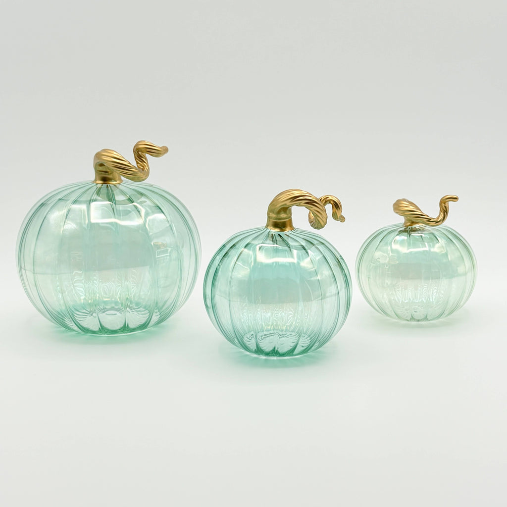 Three glass pumpkins with gold stems on a white background