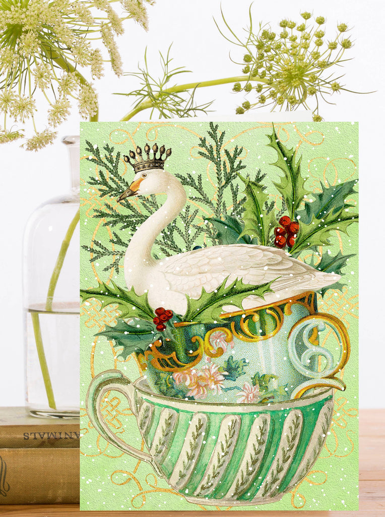 Card with a swan in a teacup surrounded by greenery and flowers on a light green background.