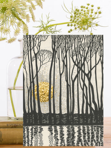 Greeting card with black and cream outlines of trees reflected in water and a hand glittered gold sunset behind.