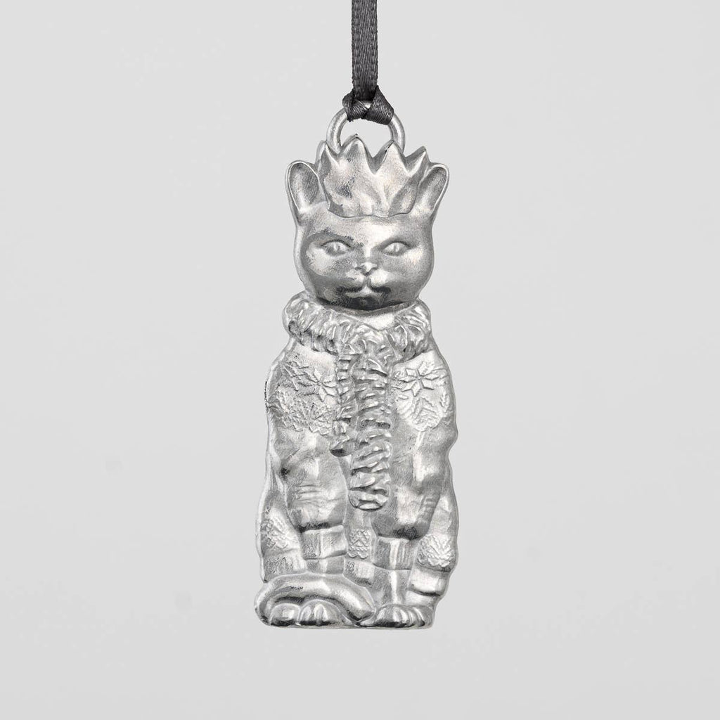 Pewter cat-shaped ornament with a crown, scarf and sweater on a gray background