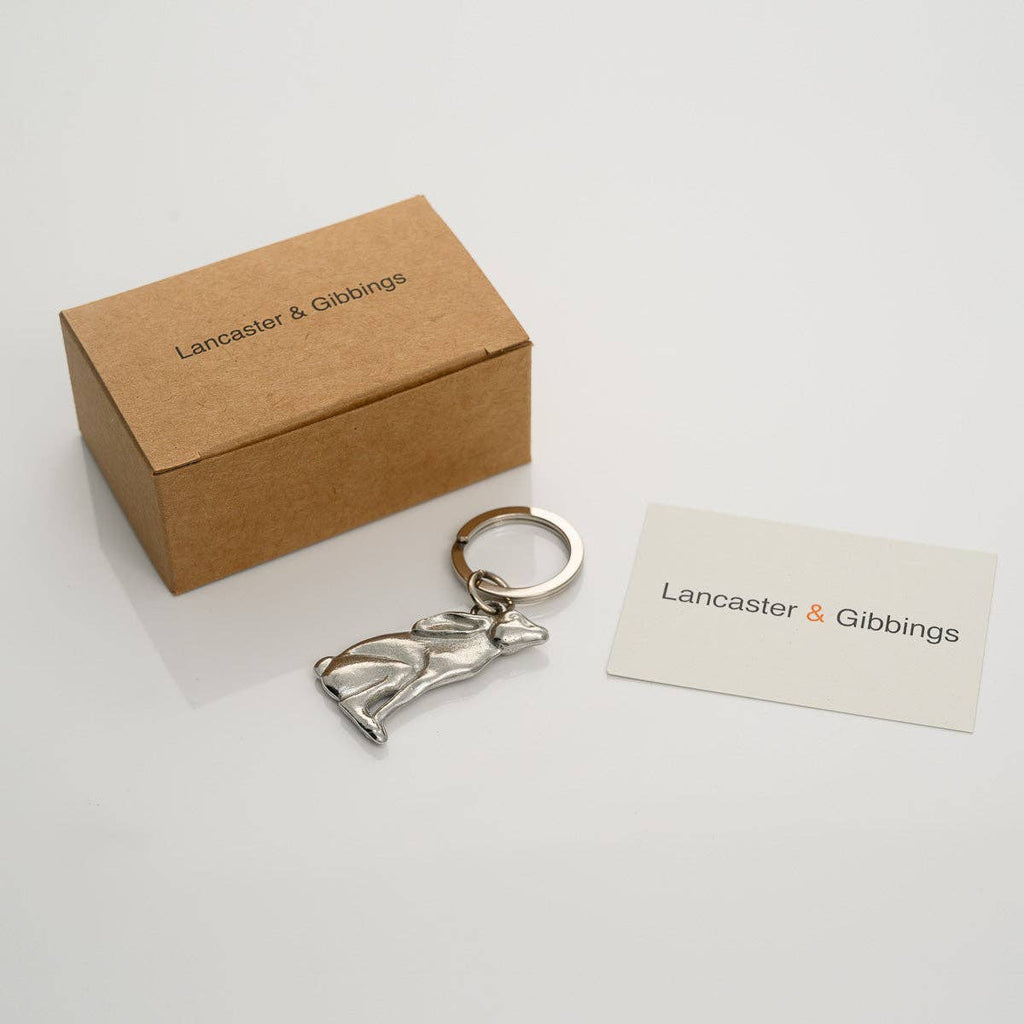 Pewter hare-shaped keychain with a box and card displaying 'Lancaster & Gibbings' on a light gray background