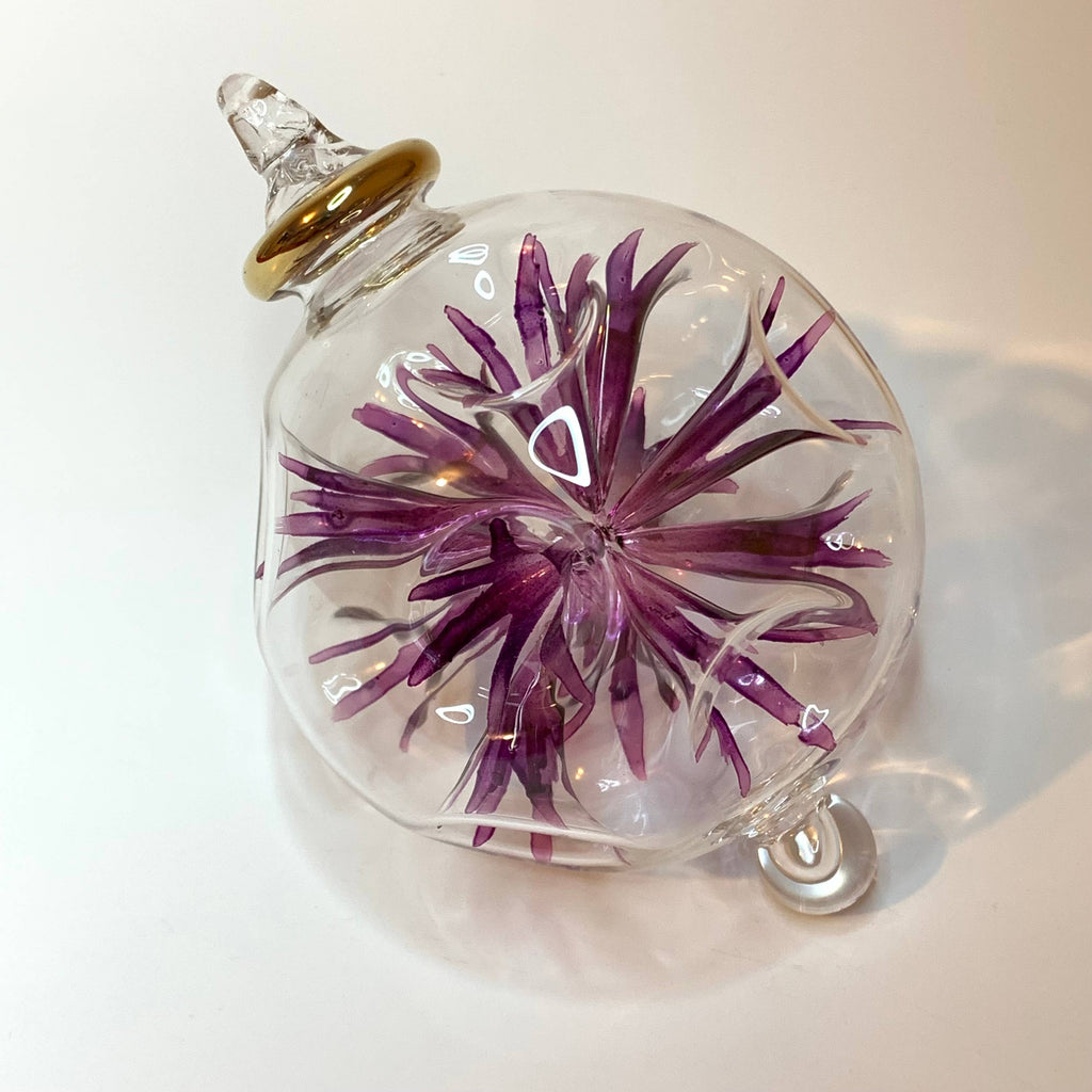 Glass ornament with a purple floral design 