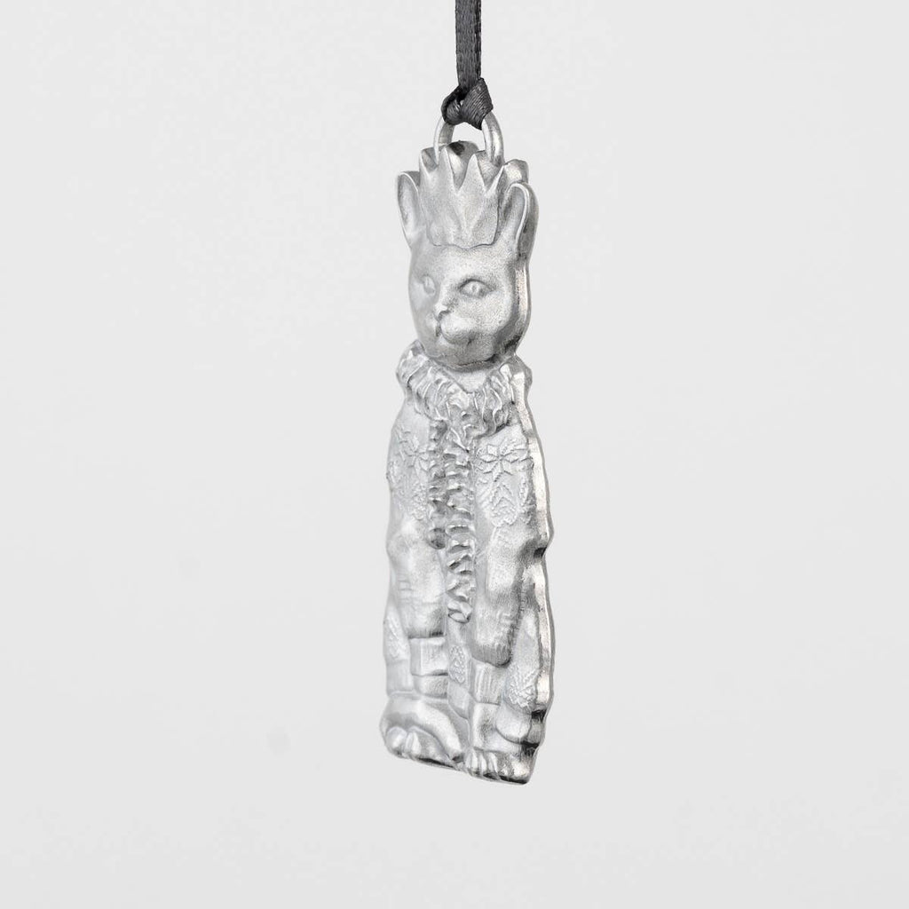 Pewter cat-shaped ornament with a crown, scarf and sweater on a gray background