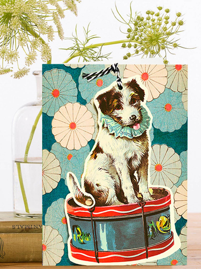 Vintage-style greeting card with a dog on a drum and a floral design.