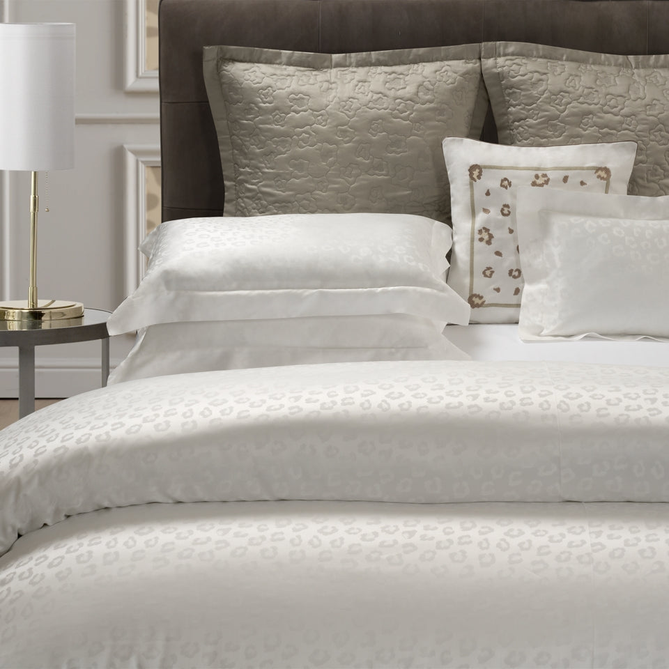 Neatly made bed with textured bedding and pillows in a bedroom setting.