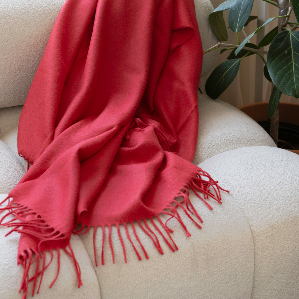 Red scarf with fringes draped over a white surface