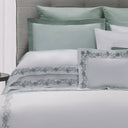 Bed with green and white bedding featuring floral embroidery, branded 'Dea Annabella'.
