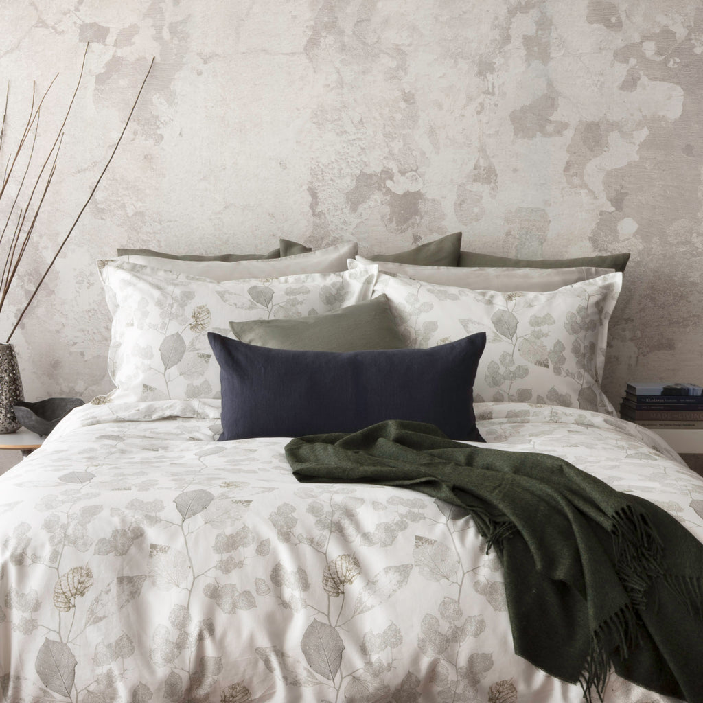 Aspen bedding display with shams and duvet cover. Included decorative elements that match the Aspen leaf prints. The decorative elements includes: Forma Juniper and Indigo cushion with Alfie Cedar throw.
