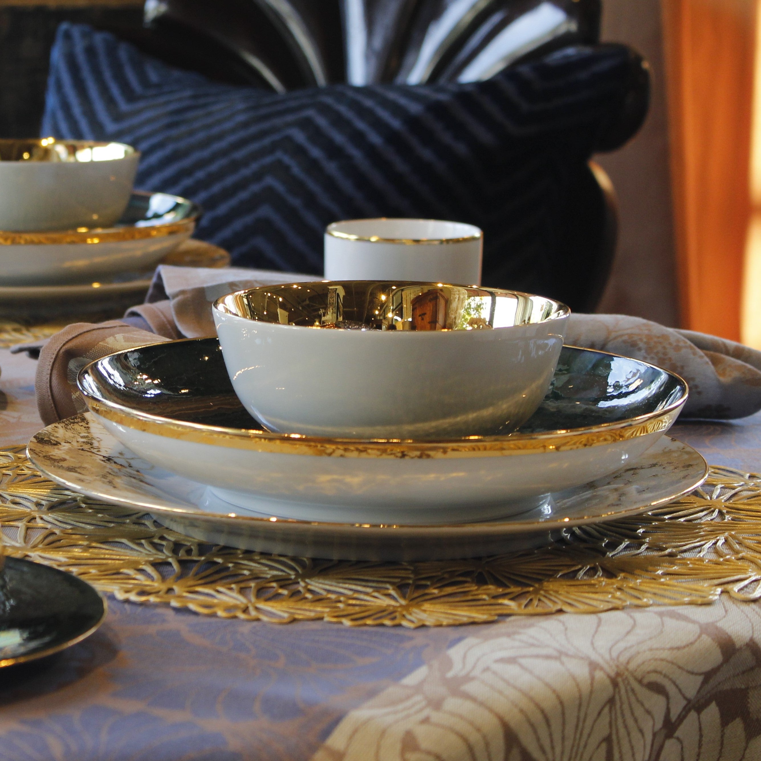 Gold accent bowl shown on table setting layered with a larger bowl and a plate underneath