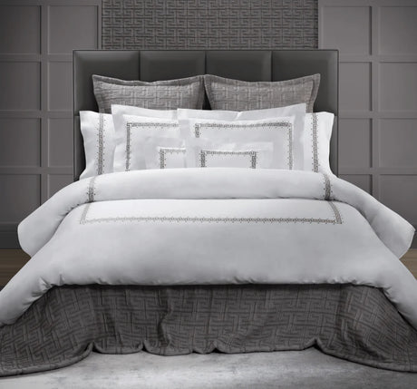 Classic greek key embroidery in grey tones on white bed linens. 