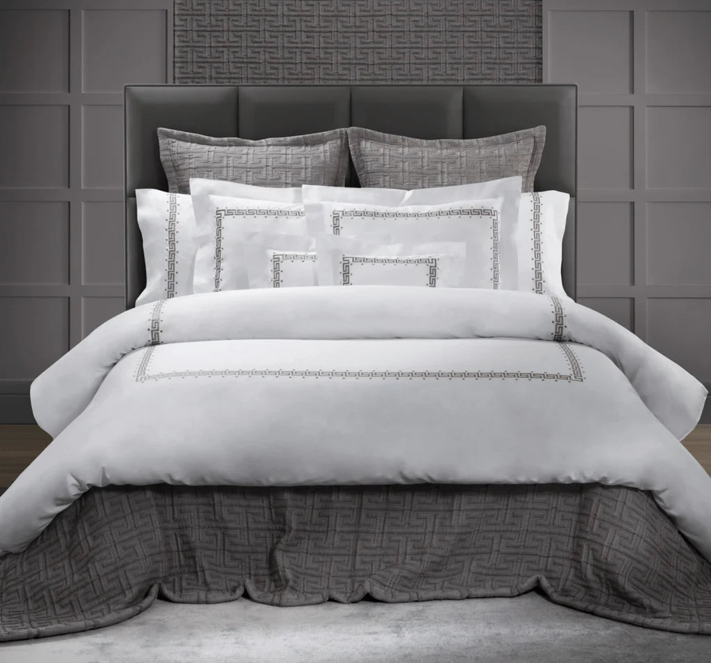 Classic greek key embroidery in grey tones on white bed linens. 