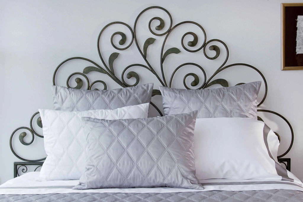 Diagonally quilted shams in Filicudi Silver Moon against  decorative iron headboard