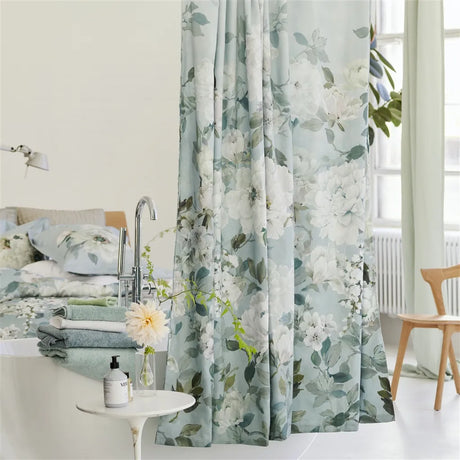 Floral curtain in a bathroom setting with toiletries and a bathtub.