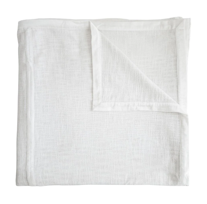 White chunky woven coverlet shown folded with one corner turned back.