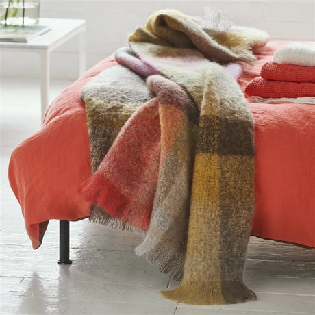 Colorful plaid blanket draped over a bed with a white background