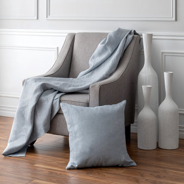 Forte Ice Throw draped on armchair with matching pillow leaning against it
