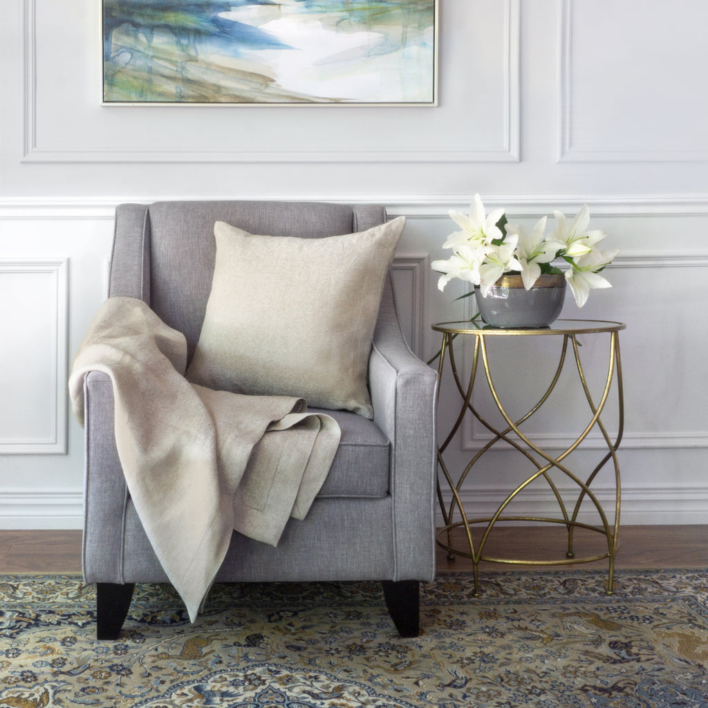 Forte Natural throw and cushion on armchair with flowers on a side table to the right