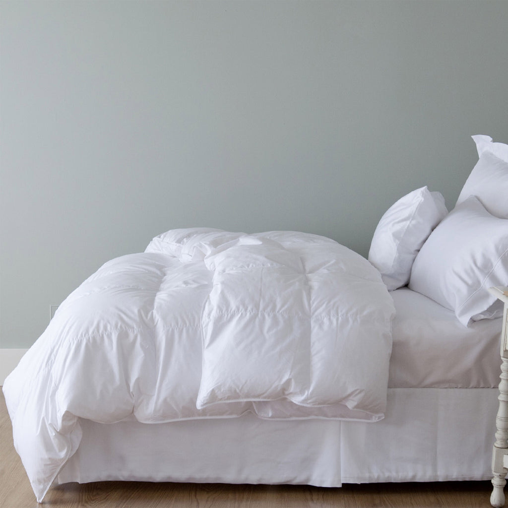 St Geneve Heirloom down duvet folded down on bed with pillows.
