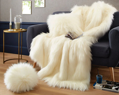 White fur throw blanket draped over a dark blue sofa in a living room setting.