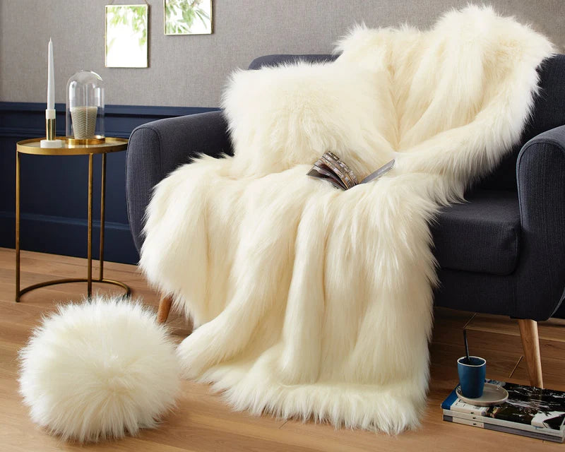 White fur throw blanket draped over a dark blue sofa in a living room setting.