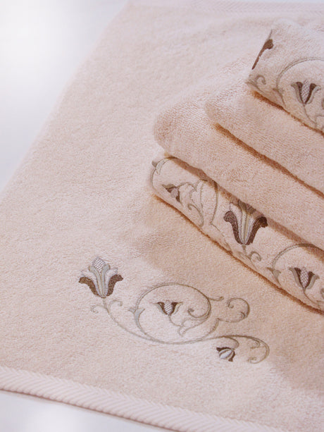 A stack of pink Tuscan towels with a flower and vine curved embroidery detail.