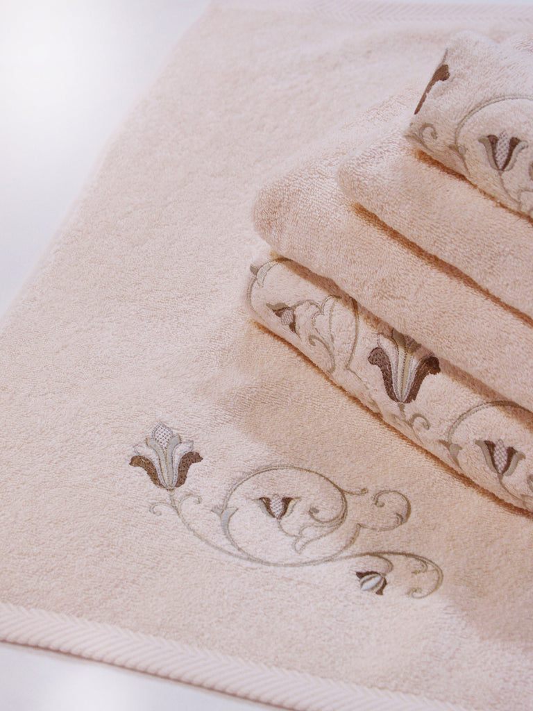 A stack of pink Tuscan towels with a flower and vine curved embroidery detail.
