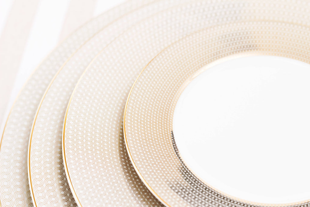 Set of white plates with gold rims on a light background