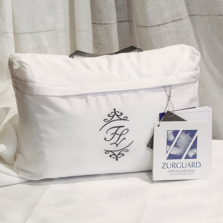 Travel pillow with Fino Lino label with Zurguard certification displayed on a bed