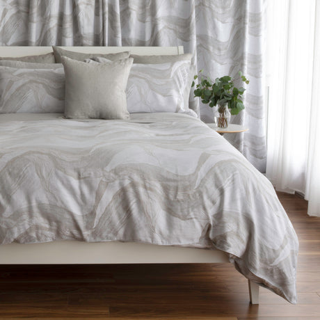 Bedding in light grey and beige tones with abstract pattern set up on the bed