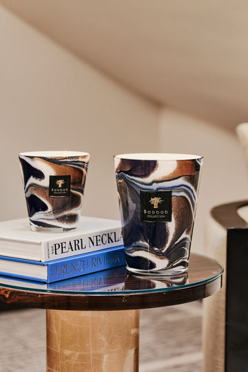 Baobab Delta Nil Max 24 and Max 16 candles shown on side table with Max 16 candle sitting on two stacked books