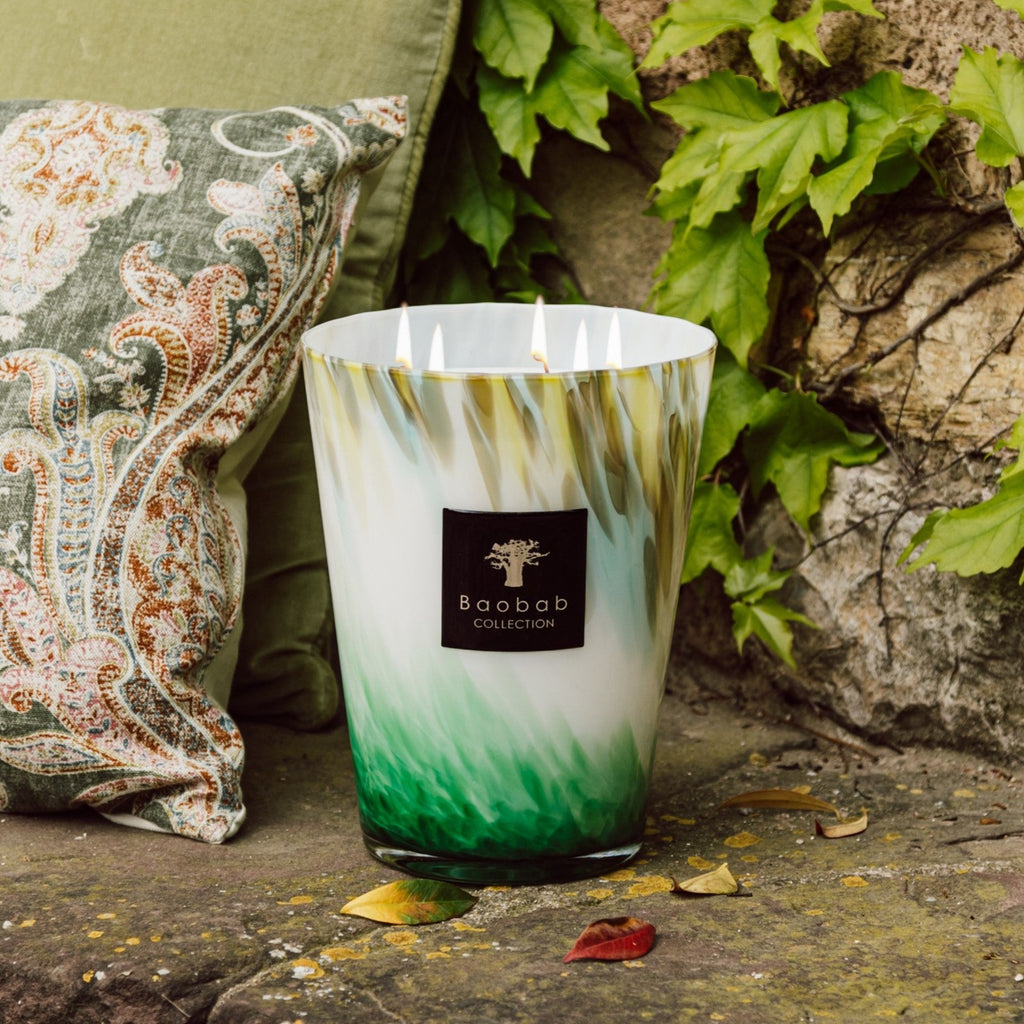 Max 16 Eden Forest Candle placed on a stone pavour in the garden behind pillows  