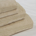 A stack of Kahki Tuscan Towels with gold Treccia embroidery details