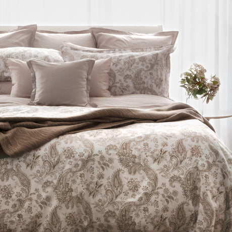 Floral bedding in light brown and beige tones is set up on a bed 