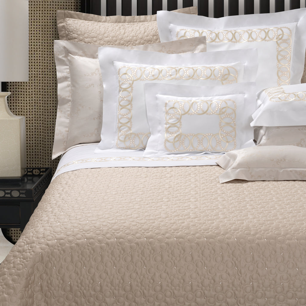 Neatly arranged bed with beige and white bedding and pillows.