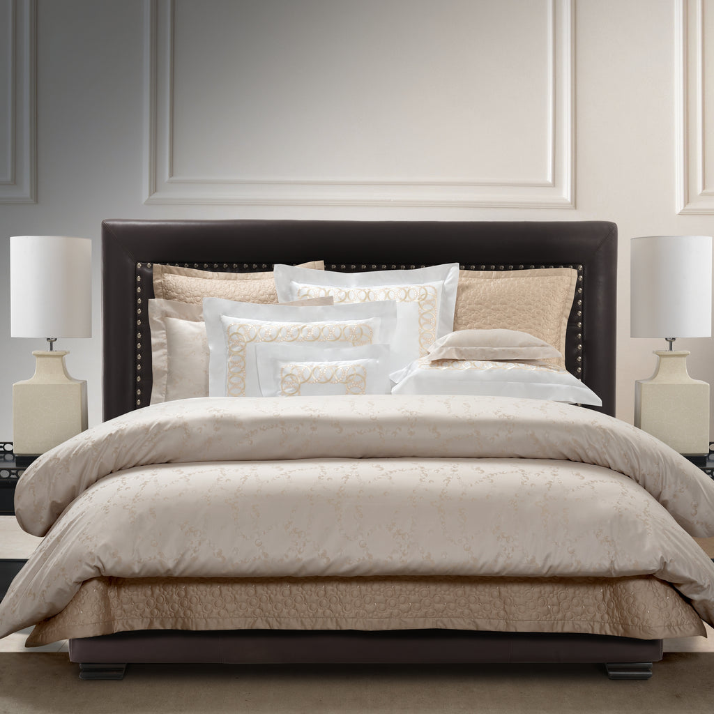 Neatly made bed with beige jacquard bedding in a bedroom setting