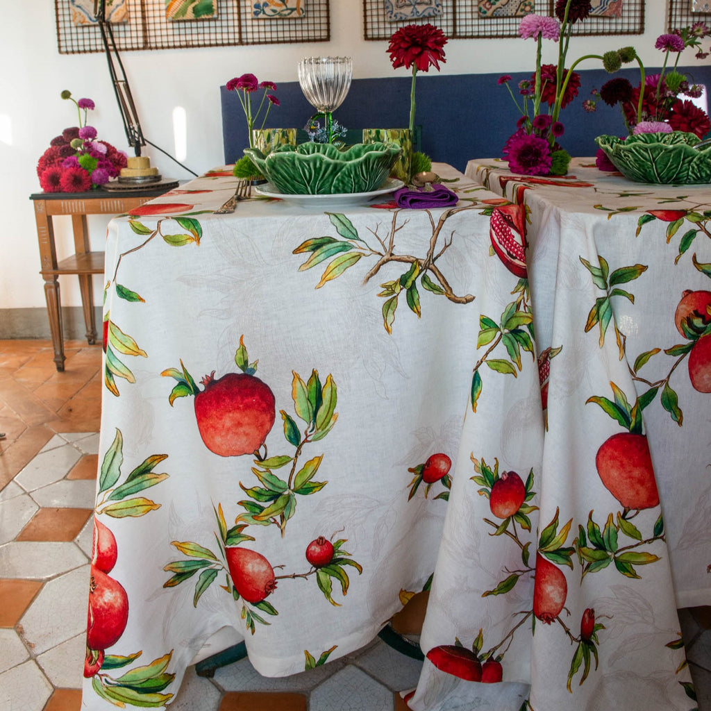 Tablecloth with pomegranate design on a dining table with floral arrangements.