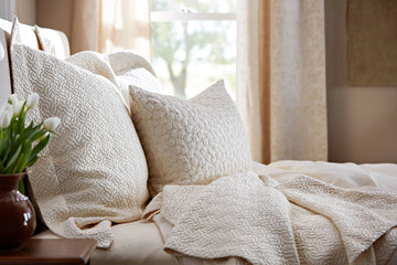 Shams and Coverlet in light beige colour placed on the bed 